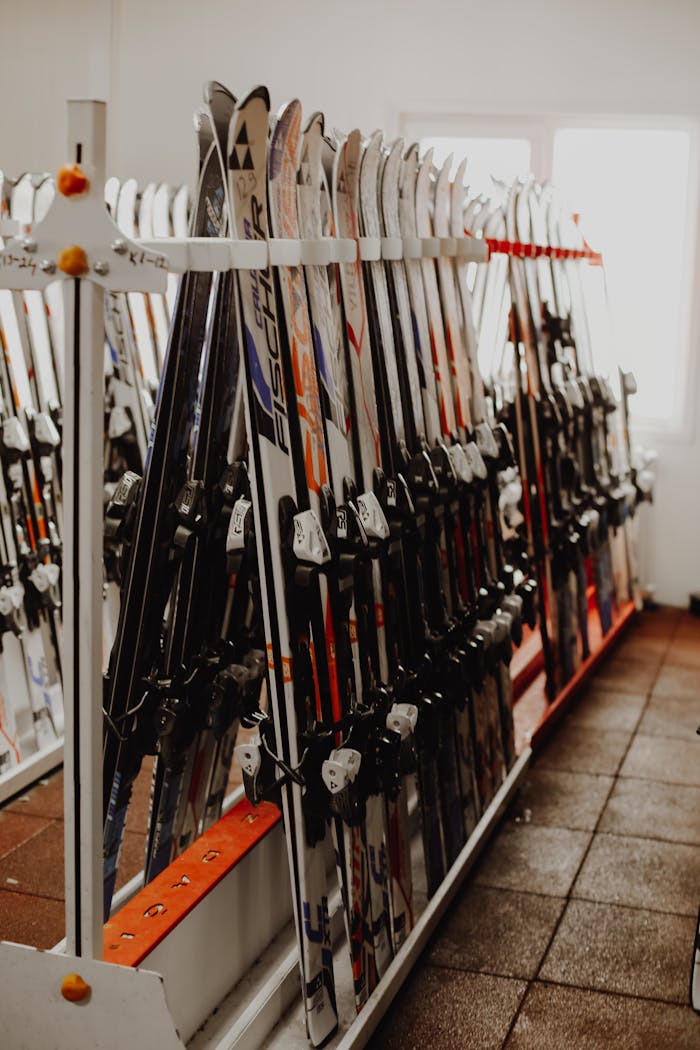 A neat arrangement of skis on a vertical rack in a well-lit indoor ski storage room.
